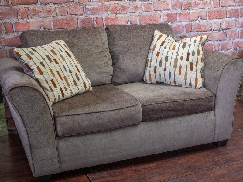 Brown loveseat with decorative pillows